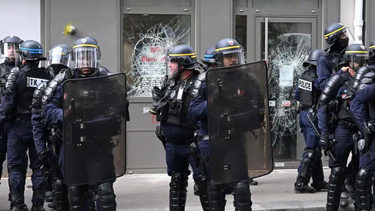 Agentes protegen un local comercial atacado por algunos manifestantes.